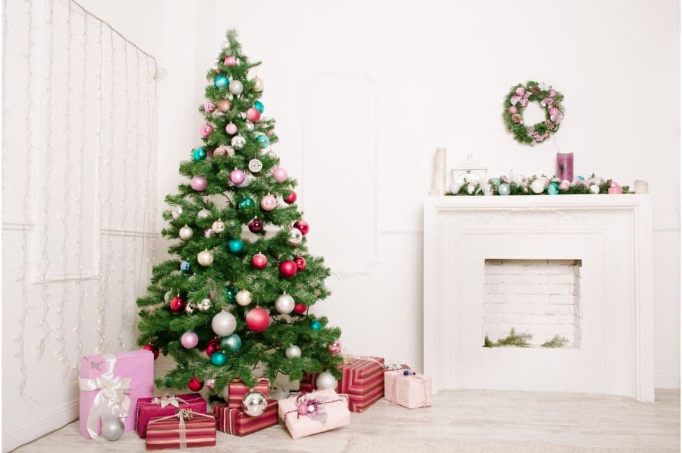 choinka ubrana w kolorowe bombki z prezentami zapakowanymi na święta w pokoju o jasnych barwach