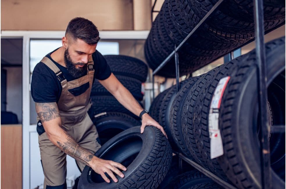 mężczyzna układający opony samochodowe w garażu