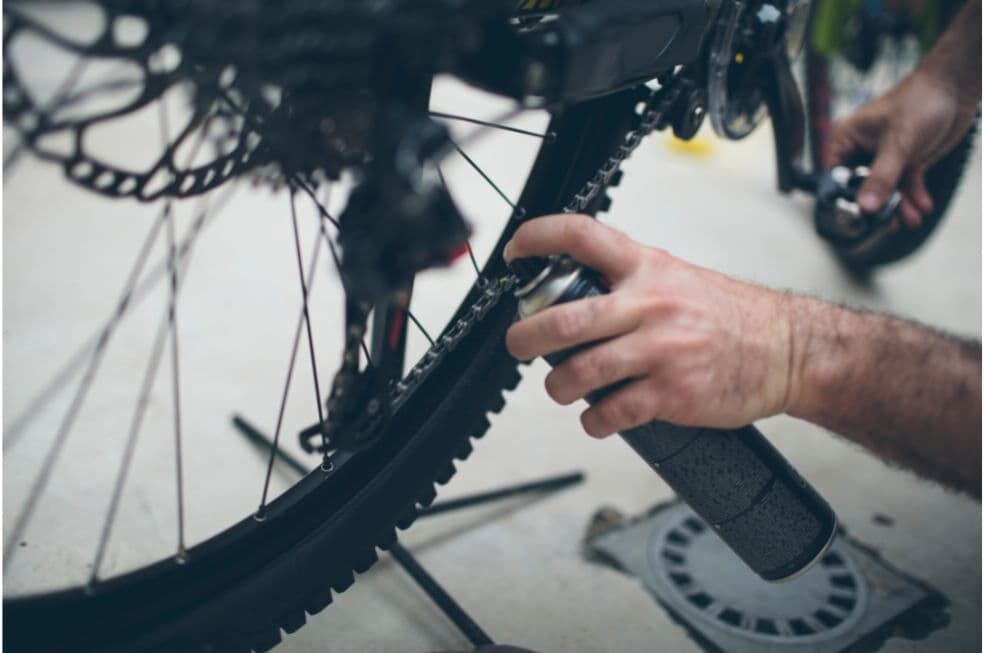 mężczyzna spryskujący łańcuch rowerowy