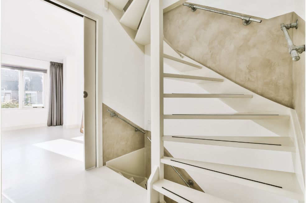 klatka schodowa w domu z białymi schodami i poręczą z metalu