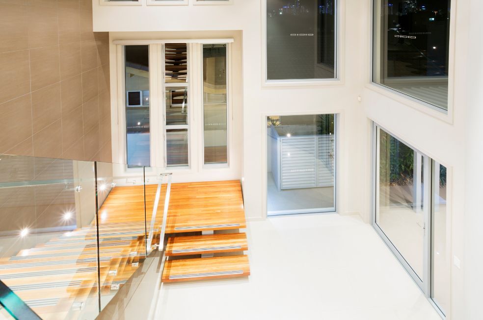 jasne, drewniane schody ze szklaną balustradą