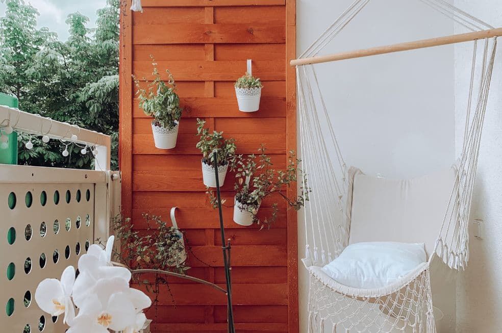 kącik na balkonie z płotem lamelowym i wiszącym fotelem ze sznurków