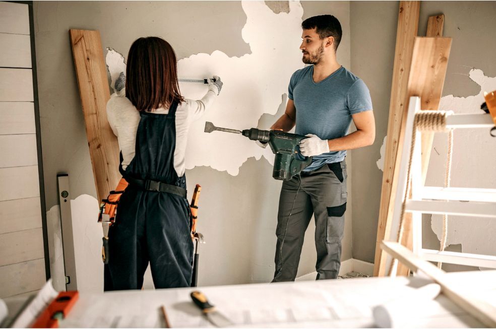 kobieta i mężczyzna robią remont ściany