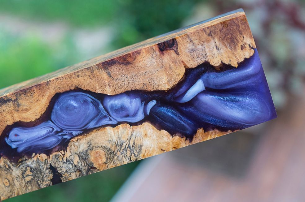 kawałek nadlanej niebieską żywicą epoksydowej deski drewnianej