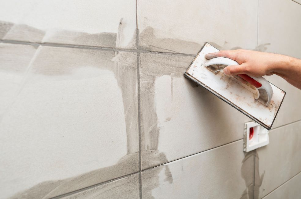 robotnik fuguje nowe płytki w łazience