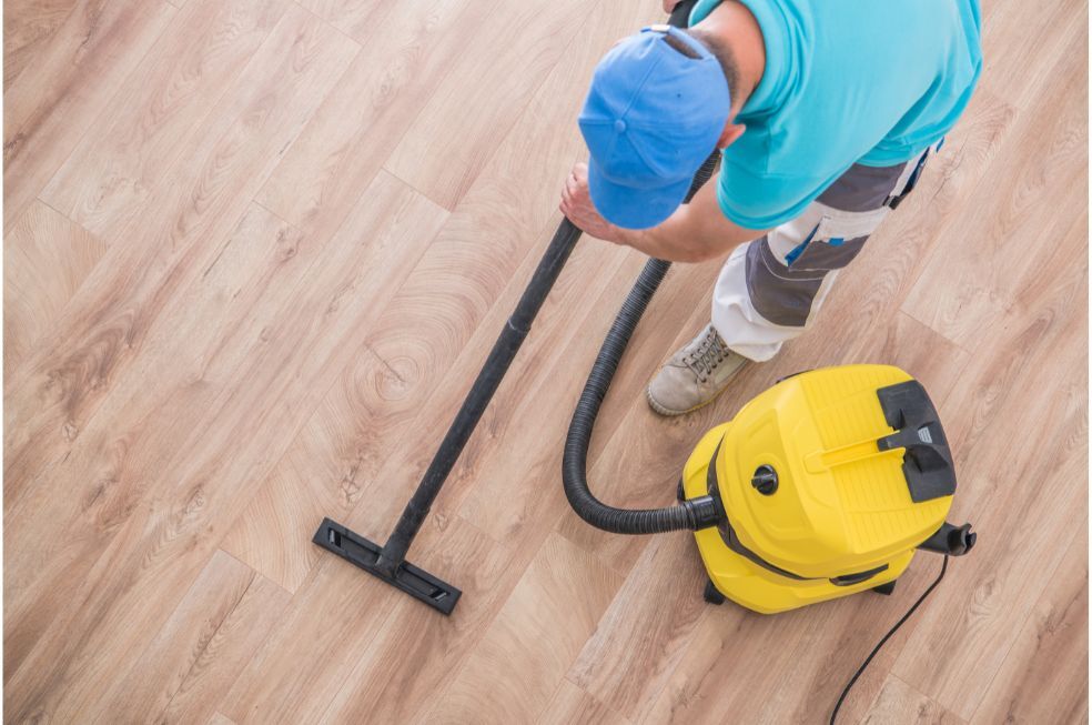 mężczyzna odkurzający panele podłogowe
