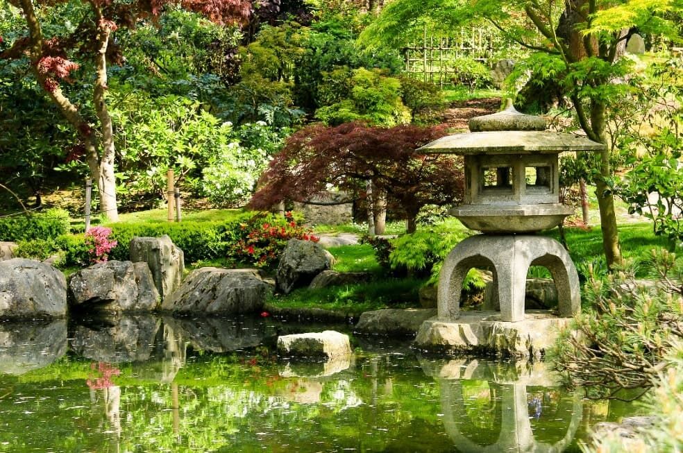kamienna rzeźba nad oczkiem wodnym w ogrodzie japońskim